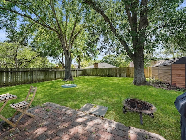 22403 Red River Dr, Katy, TX 77450 - view of yard featuring a storage shed, a fenced backyard, an outdoor structure, a patio area, and a fire pit