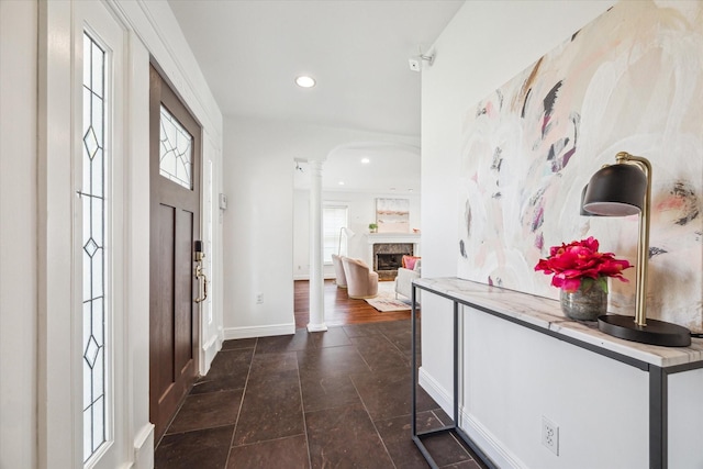 entryway with decorative columns, a fireplace, baseboards, and recessed lighting