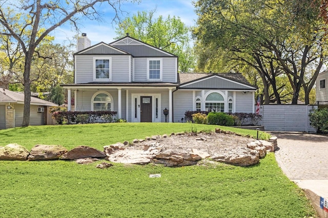 traditional-style house featuring a front yard, a porch, a chimney, fence, and driveway