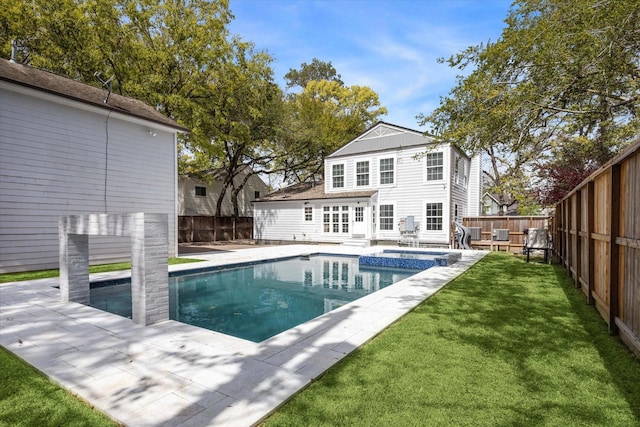 rear view of property with entry steps, a yard, a fenced backyard, and a pool with connected hot tub
