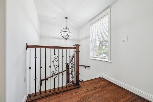 stairs with baseboards, an inviting chandelier, and wood finished floors