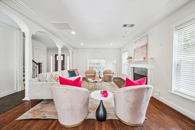 living area featuring decorative columns, a fireplace, arched walkways, visible vents, and wood finished floors