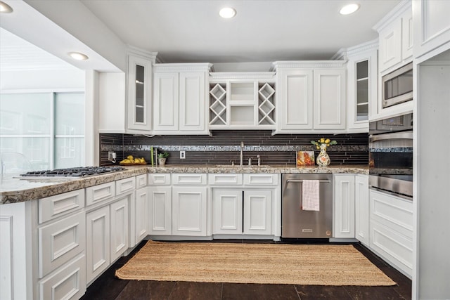 kitchen featuring tasteful backsplash, glass insert cabinets, a sink, white cabinetry, and stainless steel appliances