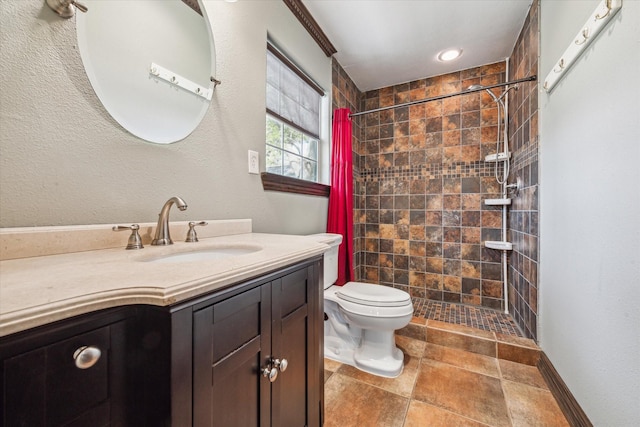 bathroom with a tile shower, vanity, and toilet