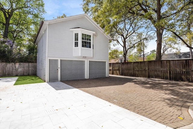 garage with decorative driveway and fence