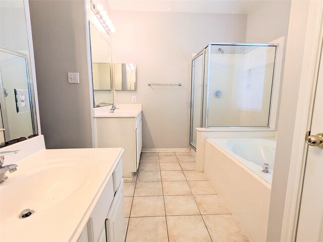 full bath featuring a garden tub, a stall shower, two vanities, a sink, and tile patterned floors