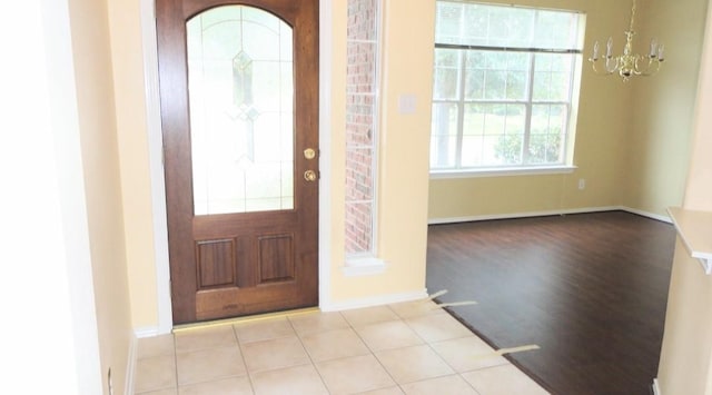 tiled entryway with baseboards and a chandelier