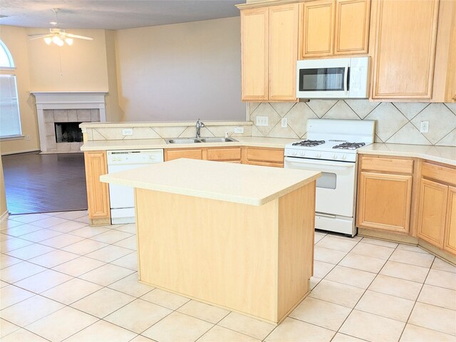 kitchen featuring ceiling fan, a sink, a peninsula, light brown cabinets, and white appliances