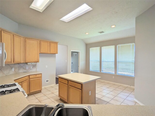 kitchen featuring visible vents, a center island, light tile patterned floors, light countertops, and a sink