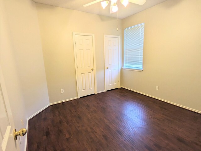 unfurnished bedroom with baseboards, a ceiling fan, and dark wood finished floors