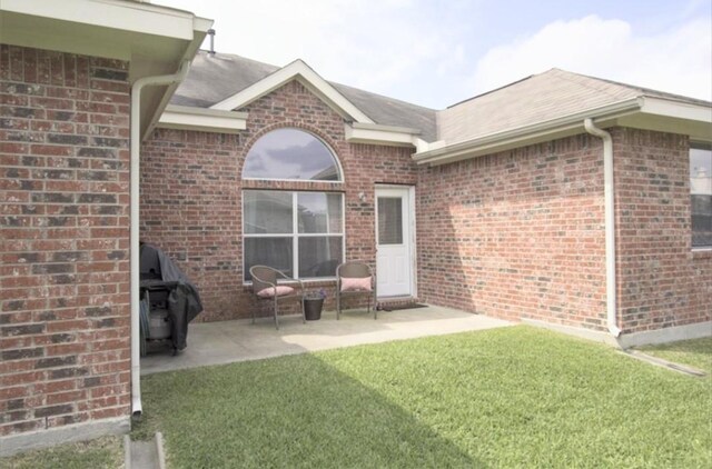 back of house featuring brick siding, a patio area, and a yard