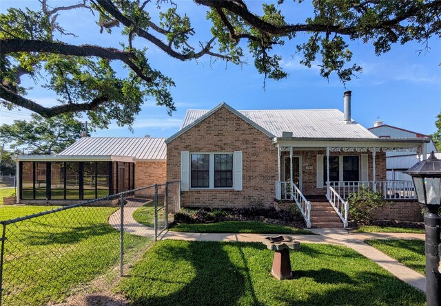 bungalow-style house featuring a porch, brick siding, a front yard, and metal roof