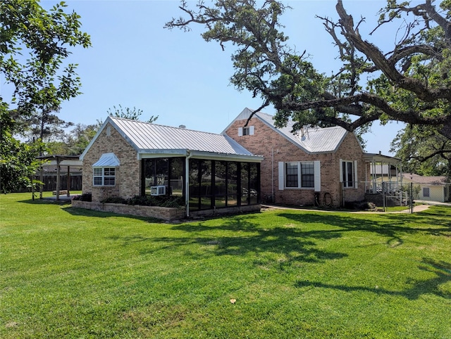 rear view of property featuring metal roof, a sunroom, brick siding, and a yard