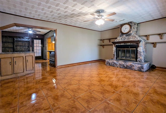 unfurnished living room featuring baseboards, a ceiling fan, and a fireplace
