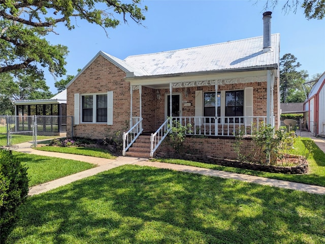 view of front of property featuring brick siding, a front yard, and metal roof