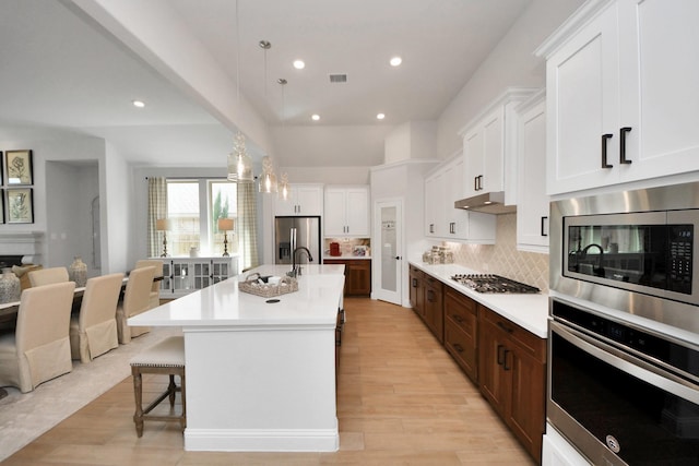 19407 Sorrel Stallion Trl, Tomball, TX 77377 - kitchen featuring visible vents, light countertops, a kitchen breakfast bar, under cabinet range hood, and stainless steel appliances