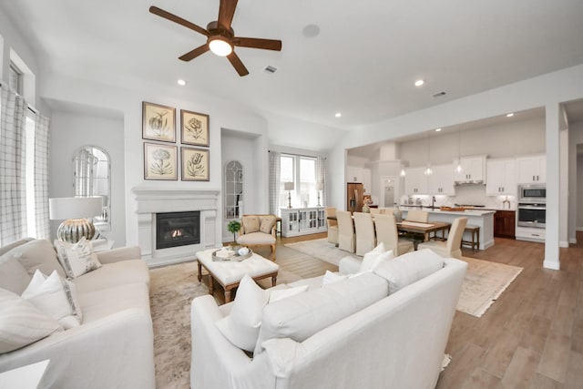 19407 Sorrel Stallion Trl, Tomball, TX 77377 - living room with visible vents, a ceiling fan, recessed lighting, light wood-style flooring, and a glass covered fireplace