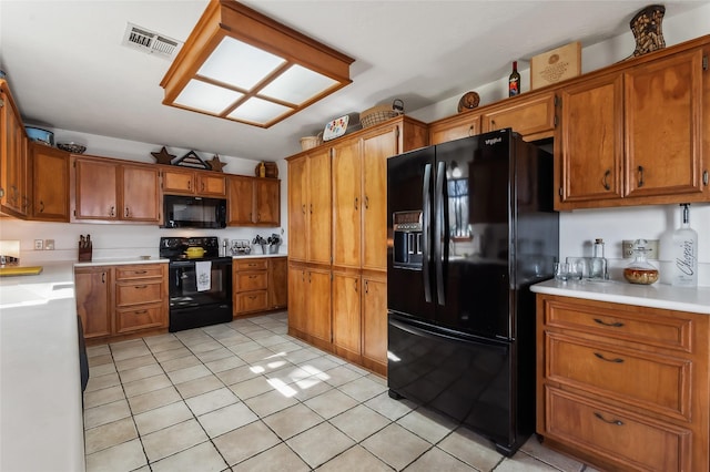 221 Kokomo Run, Point Blank, TX 77364 - kitchen featuring visible vents, light countertops, brown cabinets, black appliances, and light tile patterned flooring
