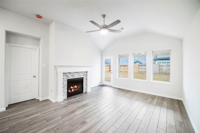 unfurnished living room with wood finished floors, ceiling fan, a fireplace, and baseboards