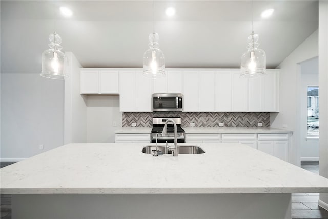 kitchen with stainless steel microwave, an island with sink, stove, and backsplash