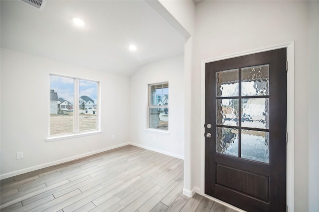 entryway with visible vents, baseboards, vaulted ceiling, and wood finished floors