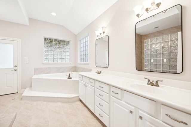 bathroom featuring a sink, double vanity, vaulted ceiling, tile patterned floors, and a garden tub