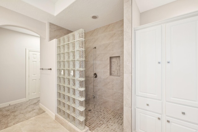 bathroom featuring tile patterned floors, baseboards, and a walk in shower