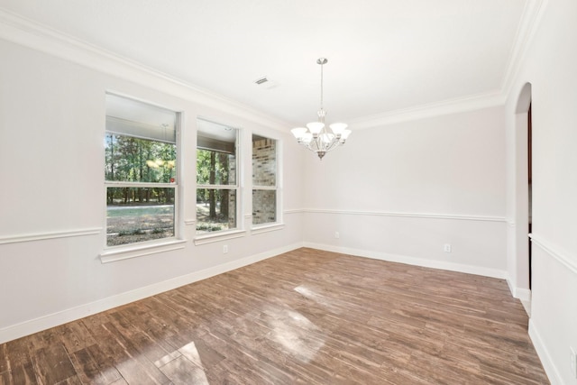 unfurnished dining area with crown molding, arched walkways, a chandelier, wood finished floors, and baseboards