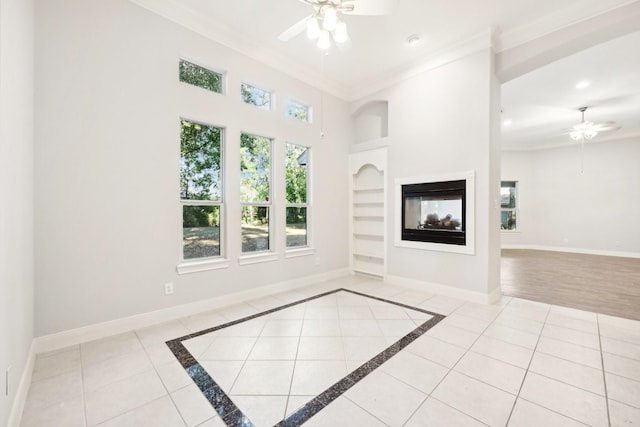 unfurnished living room featuring baseboards, crown molding, and ceiling fan