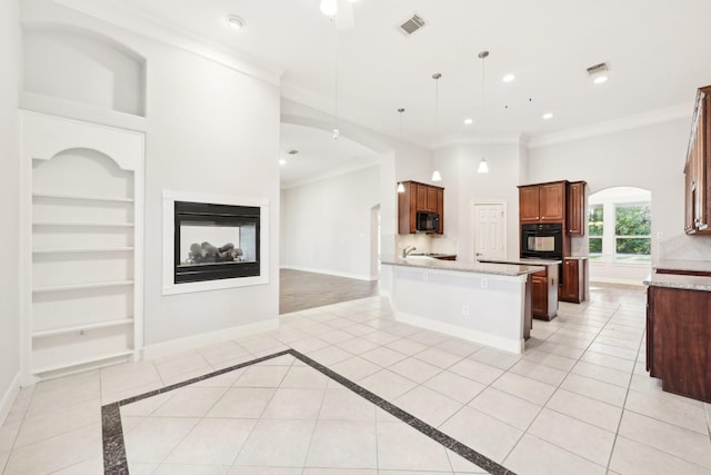kitchen with open floor plan, crown molding, built in features, and black appliances