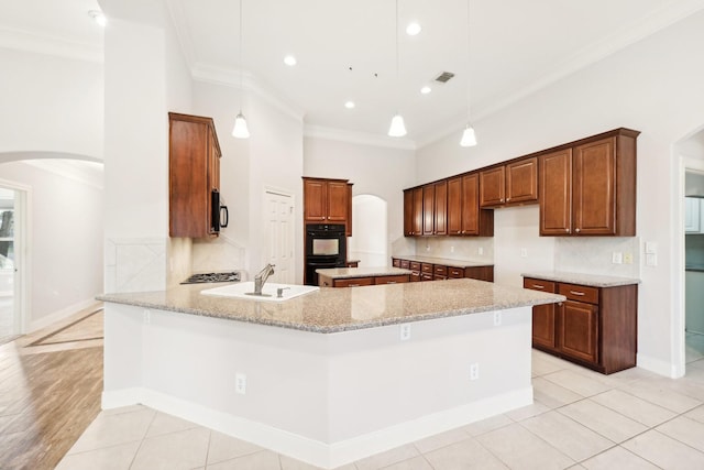 kitchen with a sink, black appliances, arched walkways, and crown molding