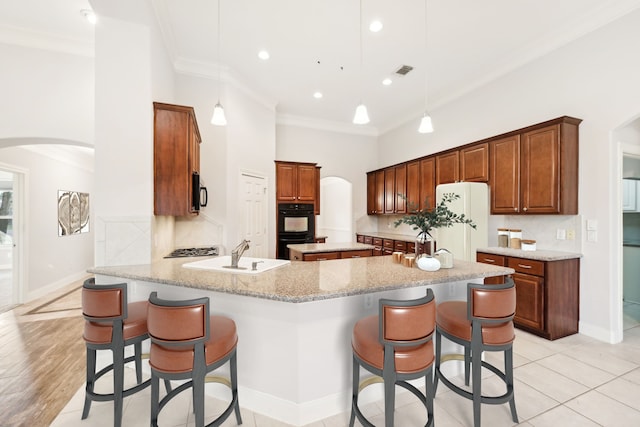 kitchen with dobule oven black, arched walkways, freestanding refrigerator, and a sink