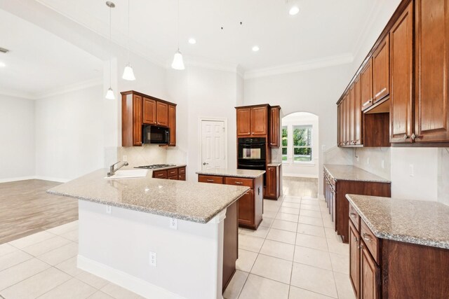 kitchen featuring light tile patterned floors, arched walkways, a sink, black appliances, and backsplash