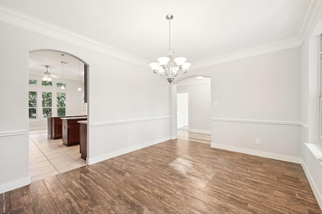 unfurnished dining area with arched walkways, light wood finished floors, ceiling fan with notable chandelier, and crown molding