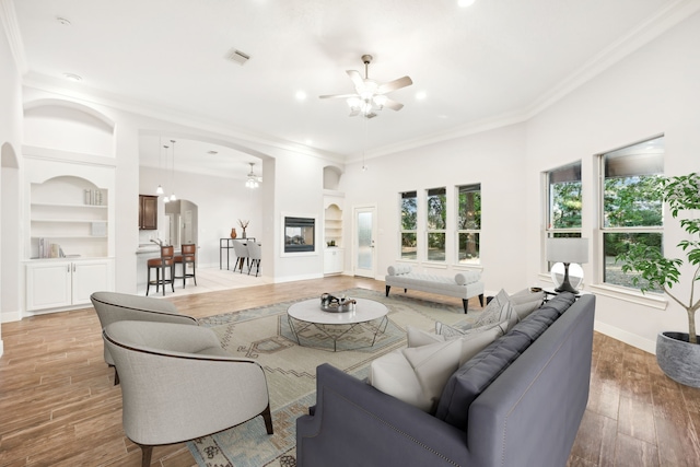 living area featuring built in features, plenty of natural light, visible vents, and ceiling fan with notable chandelier