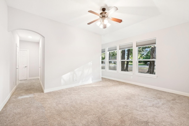 unfurnished room with arched walkways, carpet, baseboards, and a ceiling fan