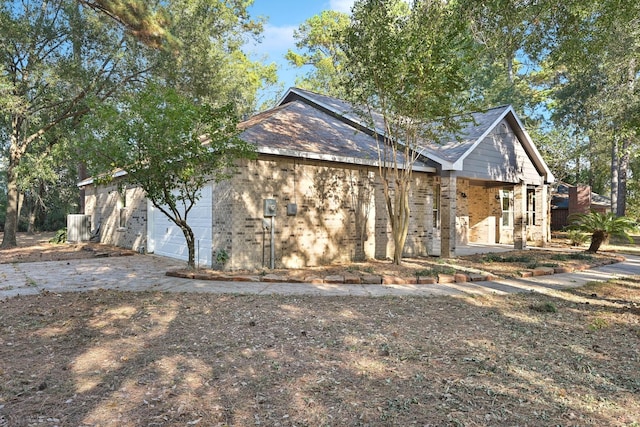 view of side of property with brick siding, driveway, and an attached garage