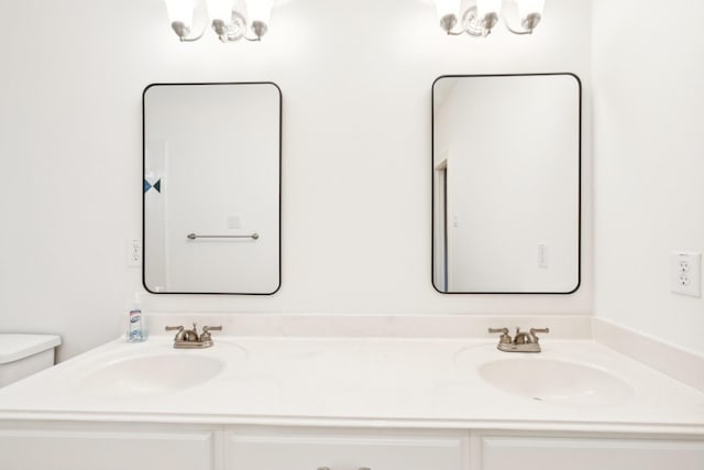 full bath featuring double vanity, a sink, and an inviting chandelier
