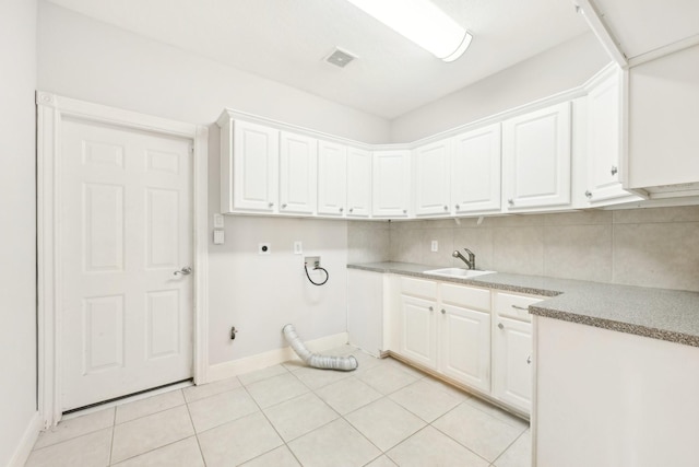 washroom with electric dryer hookup, visible vents, light tile patterned flooring, a sink, and cabinet space