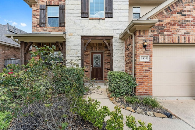 view of exterior entry featuring brick siding, a garage, and stone siding