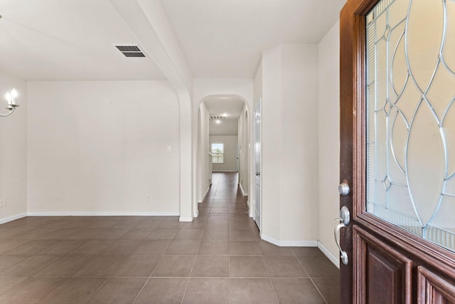 tiled entryway with visible vents, arched walkways, and baseboards