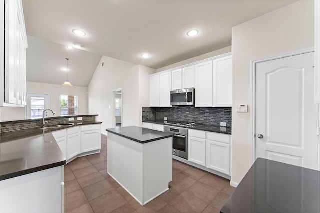 kitchen featuring dark countertops, tasteful backsplash, a sink, white cabinets, and stainless steel appliances