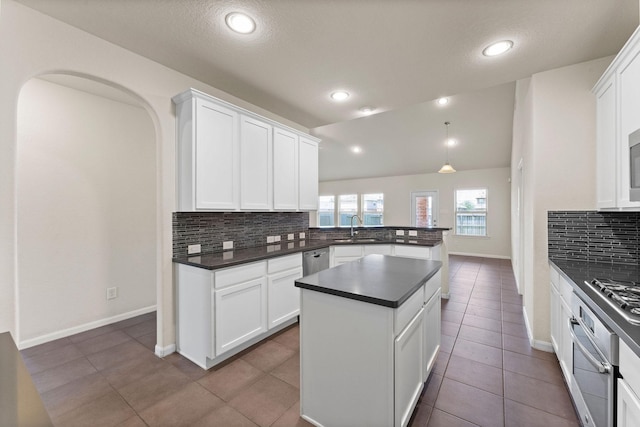 kitchen with white cabinets, dark countertops, appliances with stainless steel finishes, a sink, and decorative backsplash