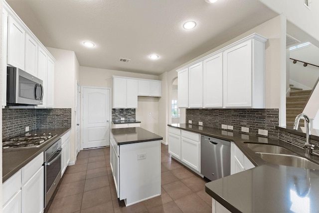 kitchen with a sink, tasteful backsplash, dark countertops, and stainless steel appliances