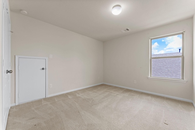 spare room with baseboards, light colored carpet, and visible vents