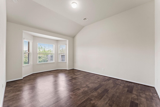 unfurnished room with baseboards, vaulted ceiling, wood finished floors, and visible vents