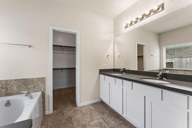 bathroom featuring a garden tub, a sink, a walk in closet, and double vanity
