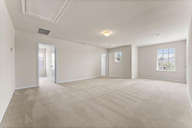 spare room with baseboards, light carpet, attic access, and visible vents