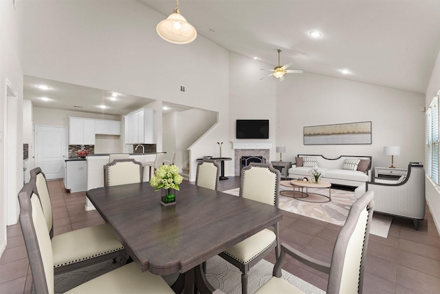 dining area featuring tile patterned flooring, lofted ceiling, a fireplace, recessed lighting, and a ceiling fan