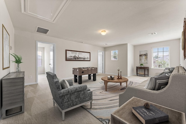 living room featuring baseboards, attic access, light colored carpet, and visible vents